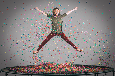 Like a star. Mid-air shot of beautiful young woman jumping on trampoline with confetti all around herの写真素材