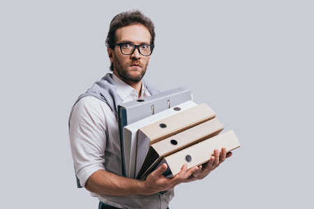 No way! Handsome young man in smart casual clothes carrying archives and looking at camera while standing against grey backgroundの写真素材