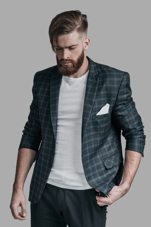 Thinking about something. Beautiful man with long hair and beard standing against grey backgroundの写真素材