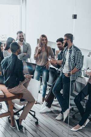 Team working together.  Group of young modern people in smart casual wear discussing something in their office の写真素材