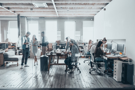 Team at work. Group of young business people in smart casual wear working together in creative office Team at work. Group of young business people in smart casual wear working together in creative office