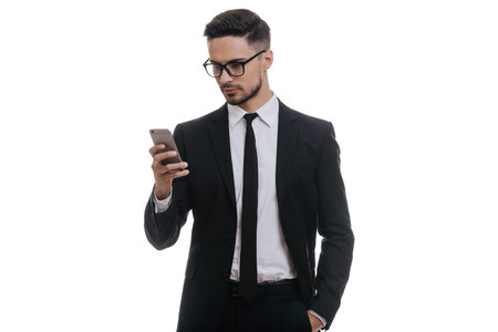 Quick chat with business partner. Serious young man in full suit typing text message using his smart...