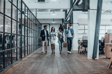 Young business professionals. Full length of young modern people in smart casual wear discussing business while walking through the office corridorの写真素材