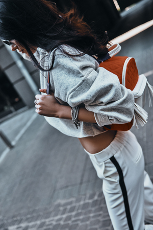Cool outfit. Young beautiful woman in sport wear carrying a backpack while walking outdoorsの写真素材