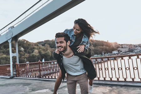 Enjoying every moment together. Young couple having fun outdoors while handsome man giving his...