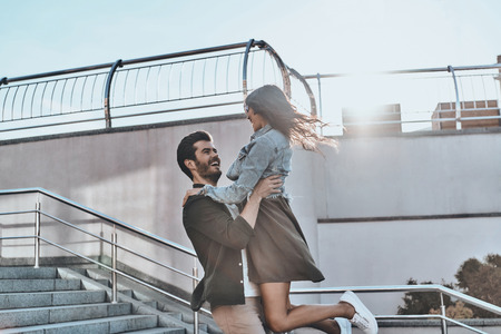 Expressing true love. Handsome man carrying young attractive woman while spending time outdoorsの写真素材