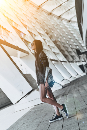 Enjoying her style. Full length of beautiful young woman in casual wear looking away while standing outdoorsの写真素材