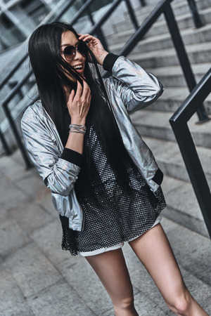 Beauty on the go. Beautiful young woman in casual wear keeping hand in hair while standing outdoorsの写真素材