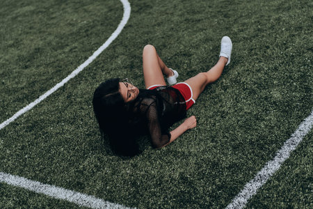 Just being herself. Beautiful young woman in sport clothing keeping eyes closed while lying on the soccer fieldの写真素材