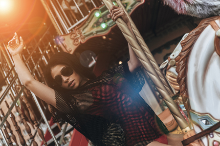 Just like a kid. Attractive young mixed raced woman in red bikini riding merry-go-roundの写真素材