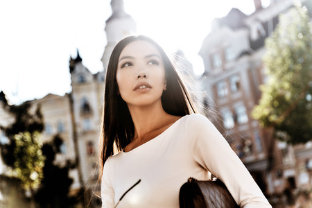 Young and beautiful. Attractive young woman looking away and smiling while standing outdoorsの写真素材