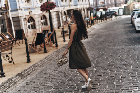 Enjoying day in the city. Full length of attractive young woman walking down the street while spending time outdoorsの写真素材