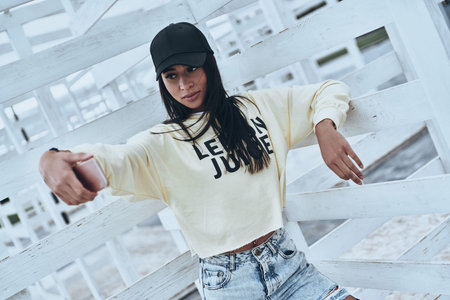 Looking perfect!  Attractive young smiling woman taking selfie while standing outdoorsの写真素材