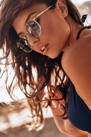 Lazy hot day. Attractive young woman in swimwear relaxing while standing on the beach outdoorsの写真素材