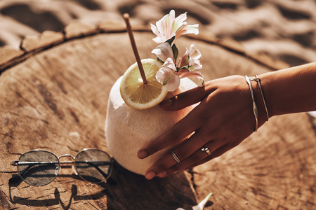 Aloha summer!  Close-up of young woman touching coconut cocktail with her handの写真素材