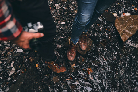 Taking a minute to rest. Close-up top view of young modern couple standing on the wet ground while enjoying their travel in mountainsの写真素材