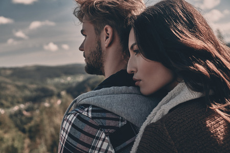 Two hearts full of love.  Beautiful young couple embracing and looking away while standing outdoorsの写真素材