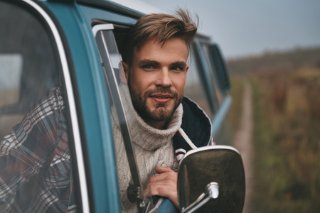Best journey. Handsome young man leaning out the van?s window and smiling while sitting on the front passenger seatの写真素材