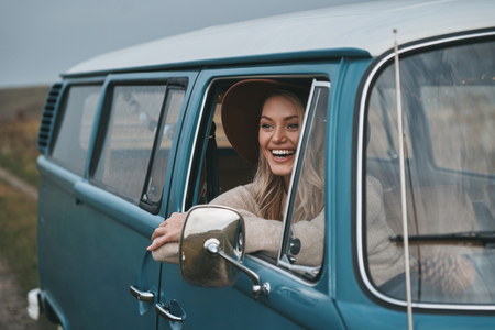 Loving this road trip. Attractive young woman looking out the van?s window and smiling while enjoying the car travelの写真素材