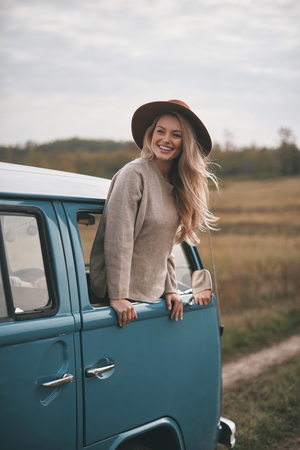 Life is awesome! Attractive young smiling woman leaning out the vans window while enjoying the car travelの写真素材