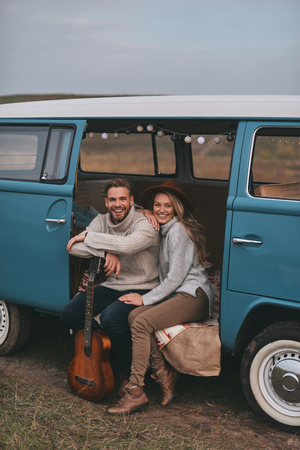 Love inspires them.  Beautiful young couple smiling and looking at camera while sitting in blue retro style mini vanの写真素材