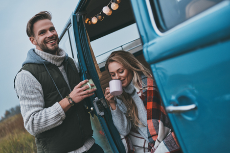 No cares and no rush.  Beautiful young couple having hot drinks and smiling while enjoying their road travelの写真素材