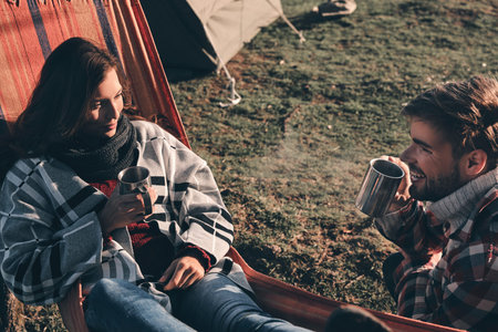 Top view of beautiful young couple having morning coffee while camping in mountainsの写真素材