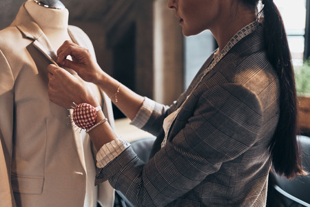 Her designs are perfect. Close up of young woman sewing a jacket on mannequin while standing in her workshopの写真素材
