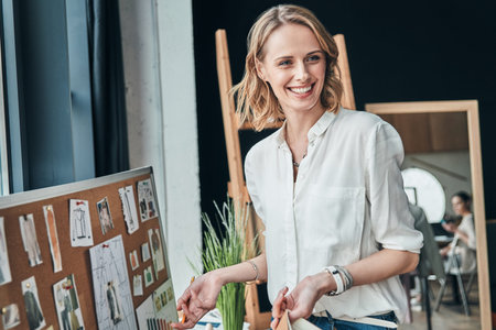 So happy. Beautiful young woman looking away and smiling while standing in the workshopの写真素材