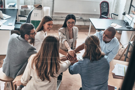 Inspired to work together. Top view of business colleagues holding hands on top of one another in a...