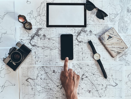 Exploring the world. Close up top view of man using smart phone with sunglasses, photo camera,...