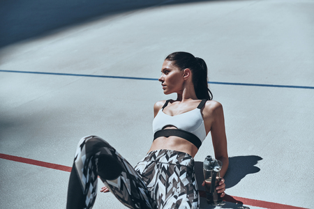 Healthy habits. Top view of young woman in sports clothing relaxing while lying on the running track outdoorsの写真素材