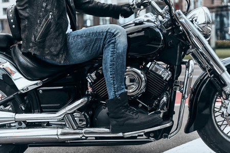 Nothing comes between him and his bike. Close up of man sitting on the motorbike while spending time outdoorsの写真素材