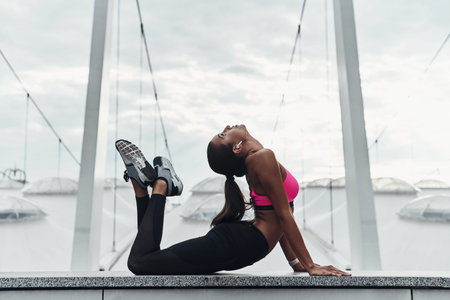 Reaching for her fitness goals. Modern young woman in sports clothing stretching while warming up...