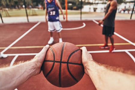 Keep playing. Close up of man holding ball while playing basketball with friends outdoorsの写真素材