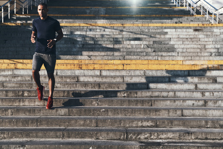 Sport is the way of life. Full length of young African man in sports clothing running down the stairs while exercising outdoorsの写真素材