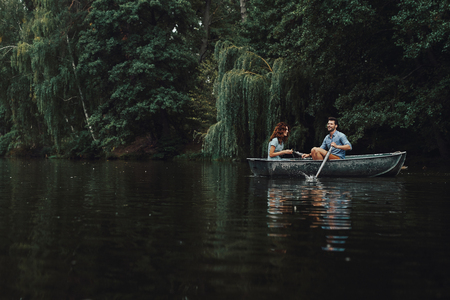 Carefree day together. Beautiful young couple smiling while enjoying romantic date on the lakeの写真素材