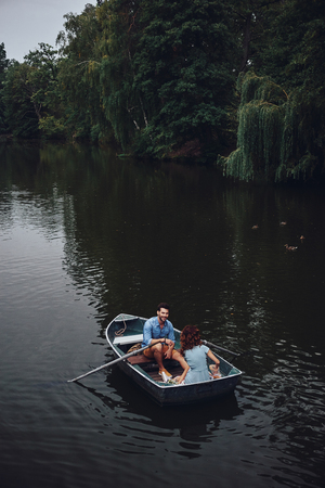 Getting away from... Top view of beautiful young couple feeding ducks while rowing a boatの写真素材