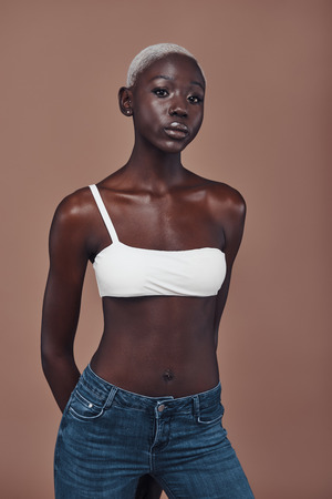 Effortless beauty. Attractive young African woman looking at camera while standing against brown backgroundの写真素材