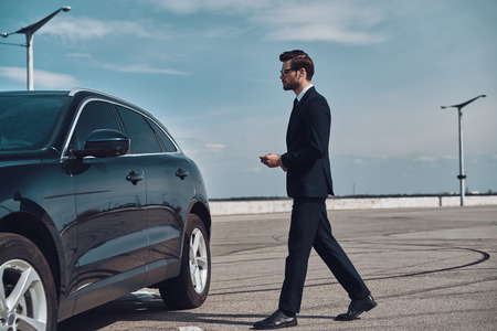 Modern businessman. Full length of handsome young businessman walking to his carの写真素材