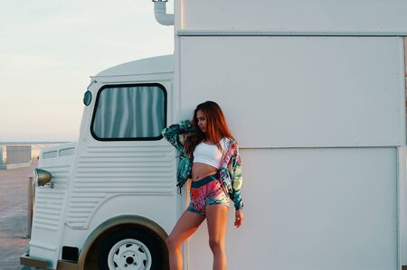Femininity. Attractive young woman in sports clothing posing while standing against food truck outdoorsの写真素材