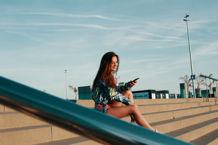 Music makes her happy. Attractive young woman in sports clothing smiling while sitting on the steps...