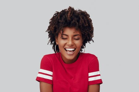 Attractive young African woman smiling while standing against grey background