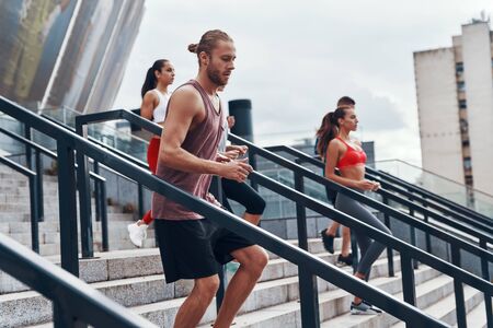 Group of young people in sports clothing jogging while exercising on the stairs outdoorsの写真素材