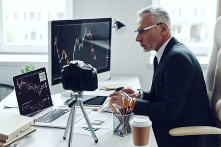 Senior man in elegant business suit using modern technologies while making social media videoの写真素材