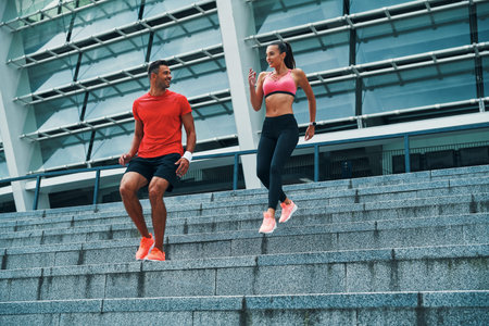 Full length of young beautiful woman and man in sports clothing enjoying morning jogging while...