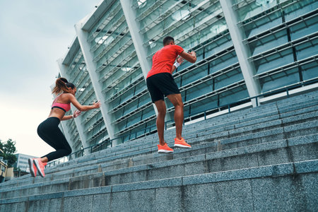 Full length of young beautiful woman and man in sports clothing enjoying morning jogging while...
