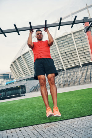 Full length of charming young man in sports clothing jogging while exercising outdoors