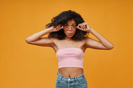 Beautiful young African woman in casual clothing adjusting her eyeglassesの写真素材