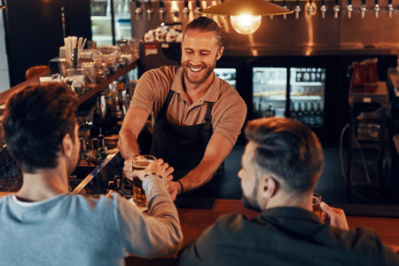 Top view of bartender serving beer to young men while standing at the bar counter in pubの写真素材